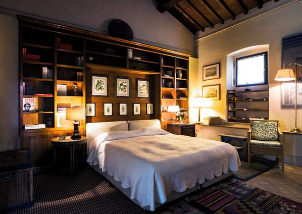 Un dormitorio bien iluminado con una cama grande, una estantería de madera y un escritorio con una silla.