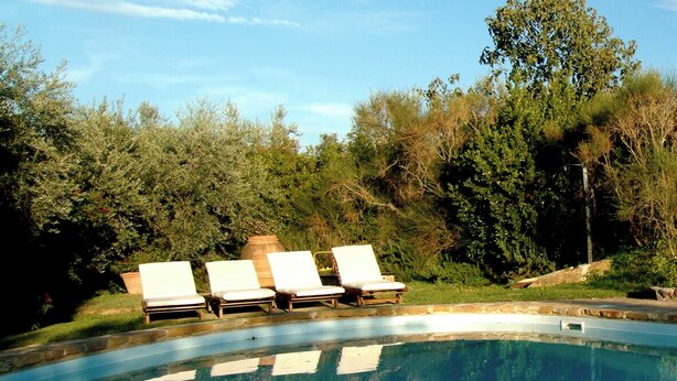 A swimming pool with three lounge chairs and a stone structure in the background. - Cottage on the Chianti Hills-Il Borghetto (San Casciano In Val Di Pesa)
