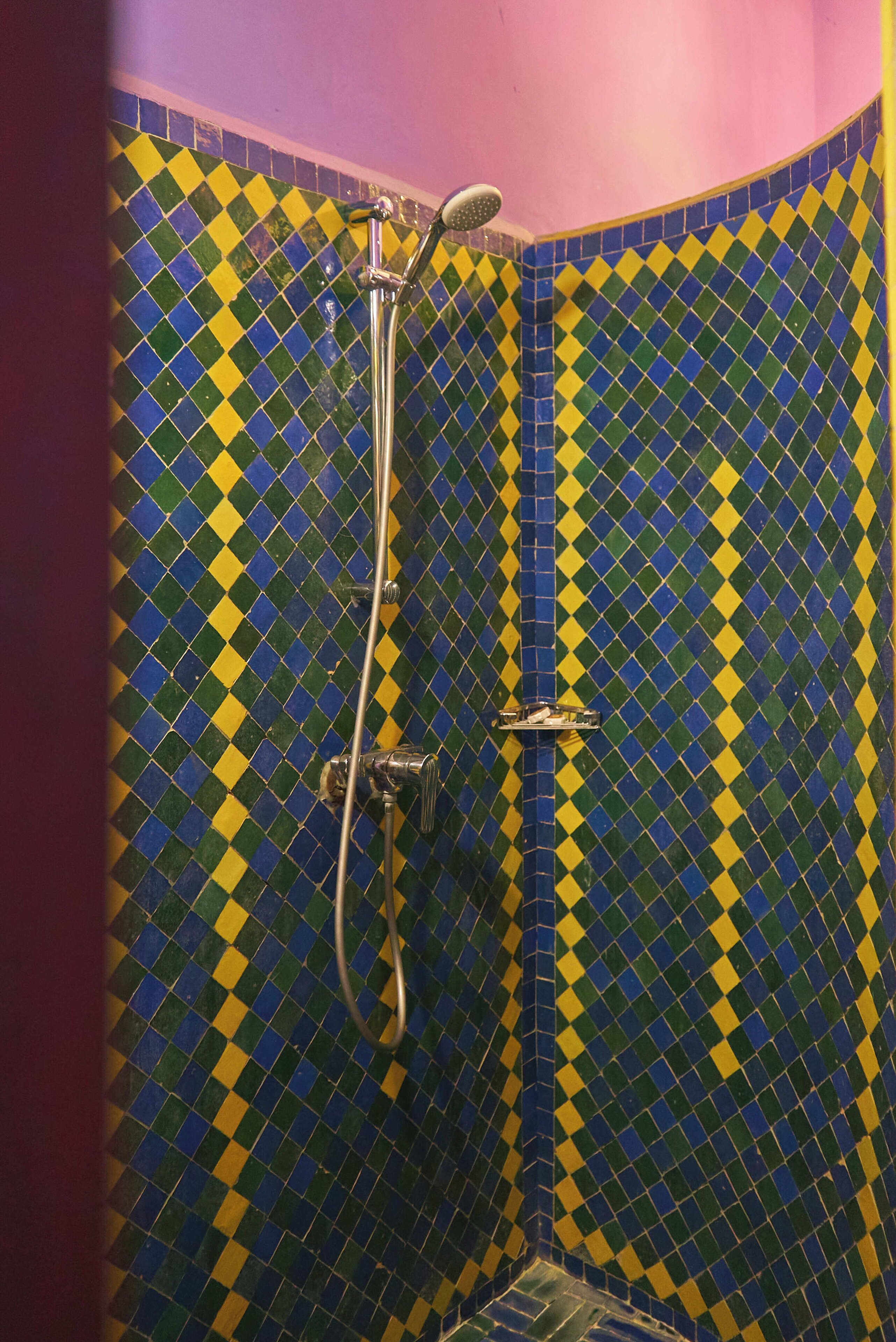A shower with a yellow and blue checkered tile pattern.