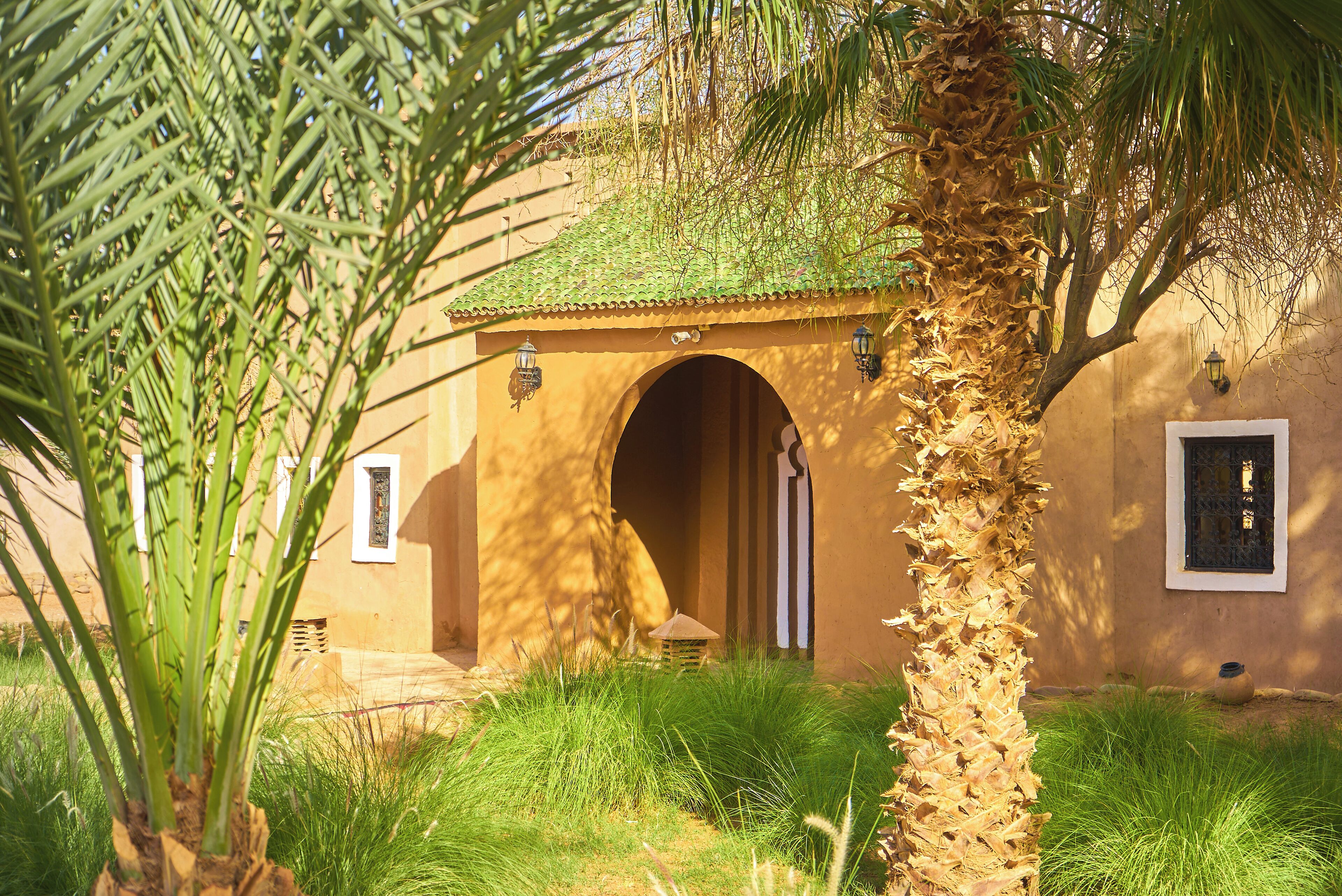 A traditional building with a tiled roof, an arched entrance, and two wall-mounted lanterns.