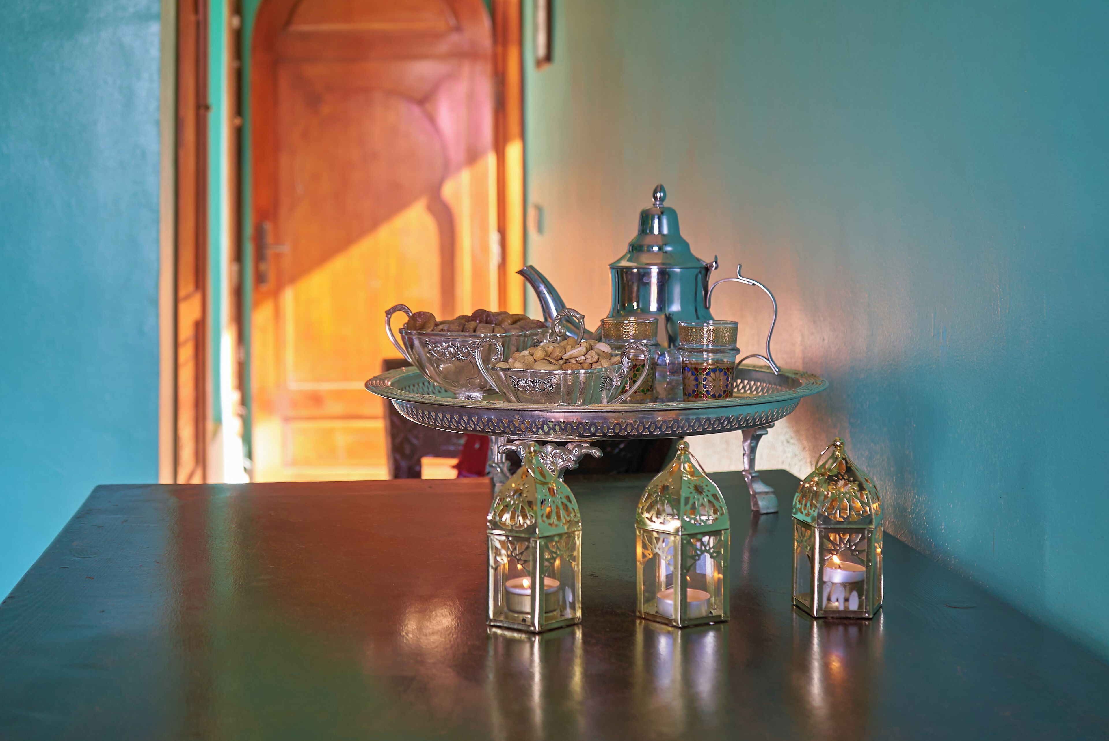 Un juego de té marroquí tradicional sobre una mesa con tres faroles de cristal.