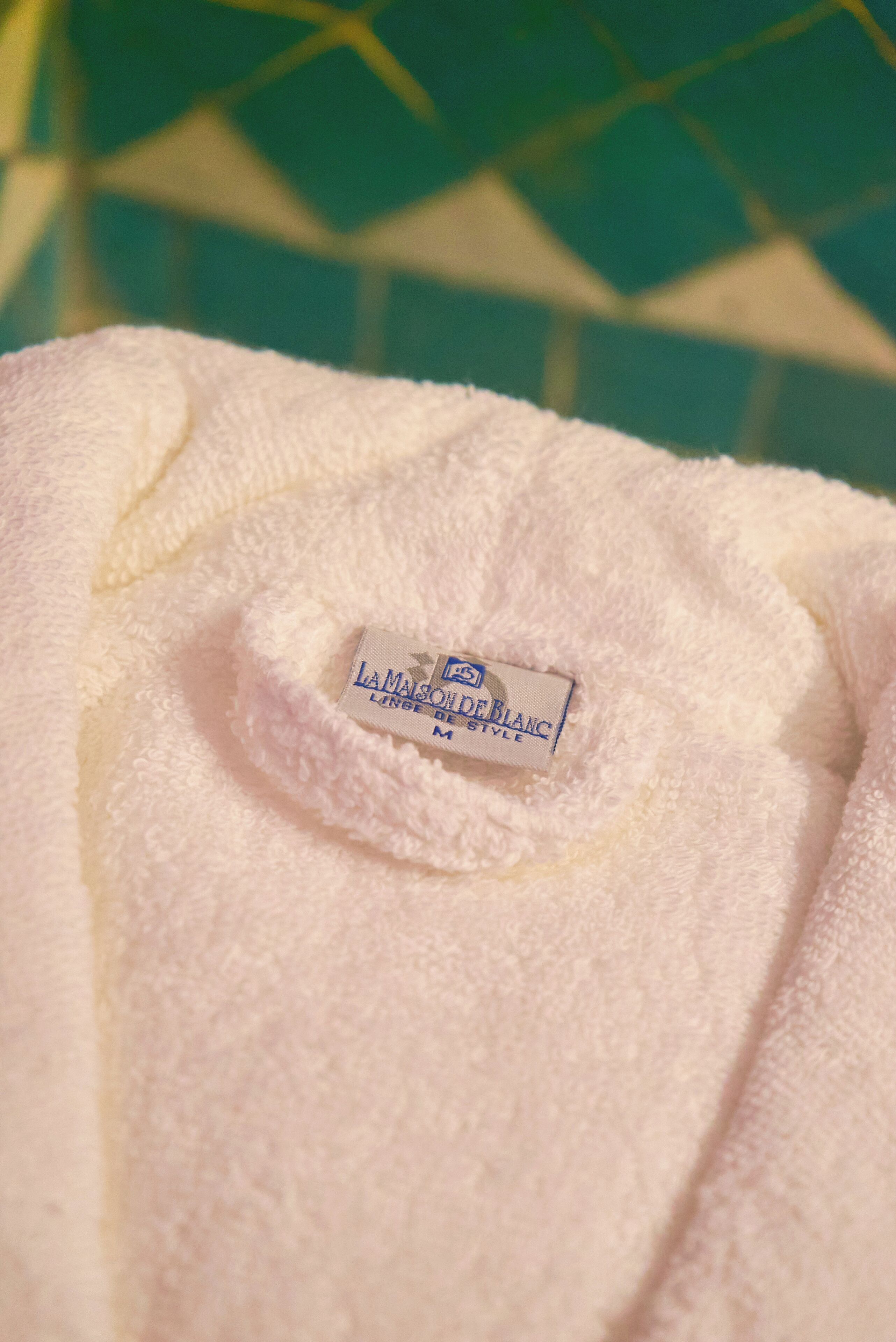 Close-up van een witte handdoek met een etiket waarop 'L'AMALSADE BLANC' staat.