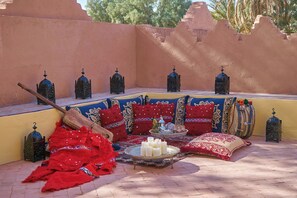 A cozy seating area with cushions, a tray with candles, and decorative lanterns. - Hotel Kasbah Azalay (M'Hamid El Ghizlane)