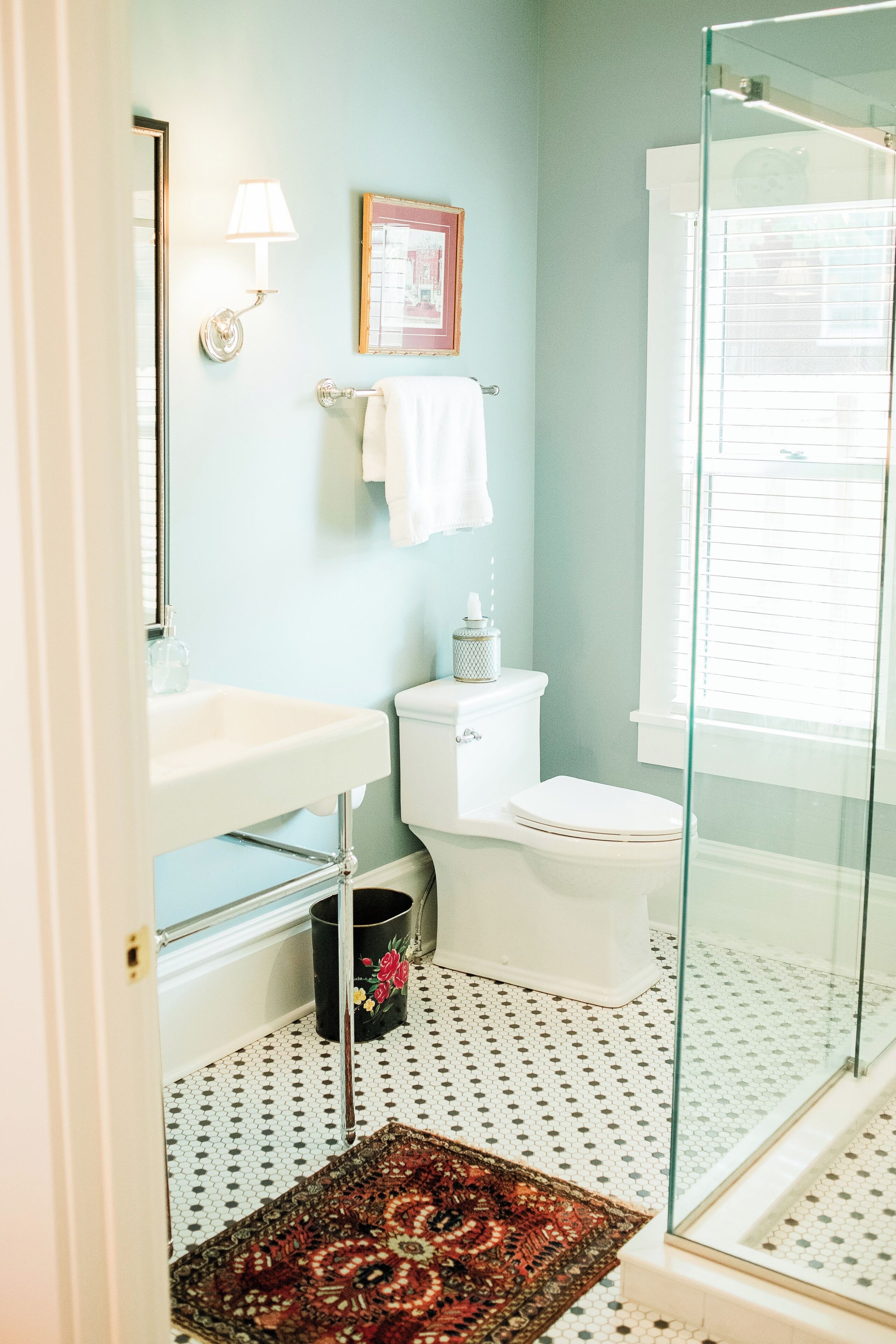 A bathroom with a toilet, sink, and glass shower enclosure.