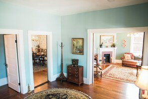 A spacious living room with hardwood floors, a fireplace, and a dining area visible through an open door.