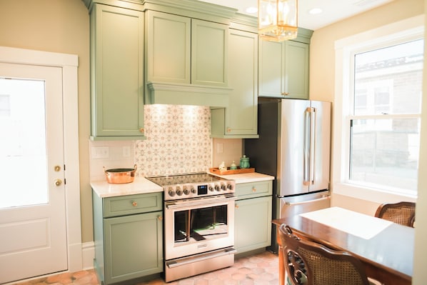 A kitchen with green cabinets, a stainless steel refrigerator, and a large oven.