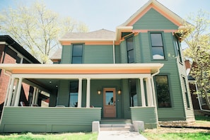 A two-story house with a front porch, a central door, and a small front yard.