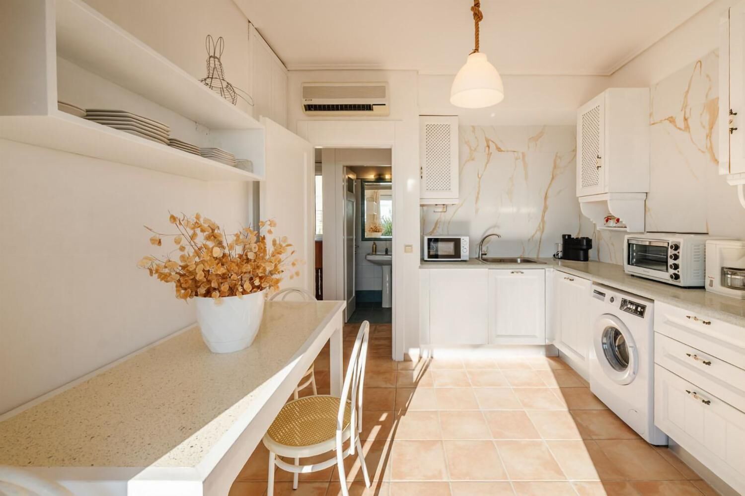 A modern kitchen with white cabinetry, a built-in washing machine, a microwave, and a toaster.
