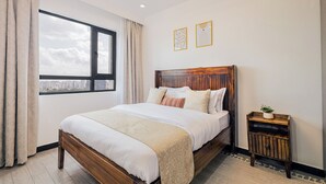 Ein Schlafzimmer mit großem Fenster, einem hölzernen Bett, einem Nachttisch und zwei gerahmten Bildern an der Wand.