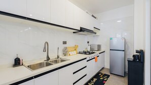 Eine moderne Küche mit weißen Schränken, einer Spüle aus Edelstahl, einem Gasherd, einer Mikrowelle und einem Kühlschrank.