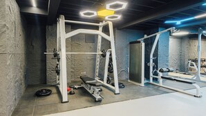 Ein Fitnessraum mit Krafttrainingsgeräten, einer Hantelbank und einem Squat-Gestell.