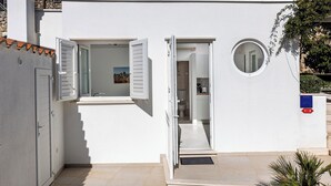 A modern white building with two open doors leading to a hallway and a bathroom. - Sunny Palace Studio 1 (Dubrovnik)