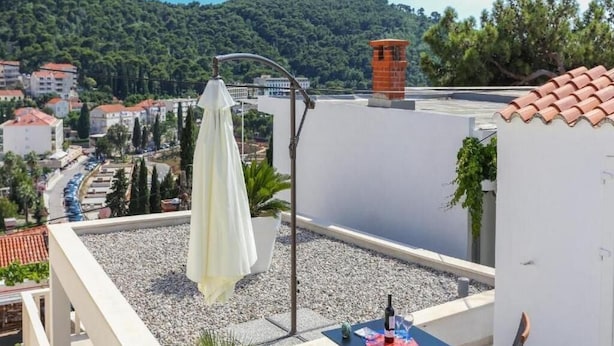 A rooftop terrace with a table, chairs, and a white umbrella. - Sunny Palace Studio 1 (Dubrovnik)