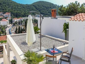 A rooftop terrace with a table, chairs, and a white umbrella. - Sunny Palace Studio 1 (Dubrovnik)