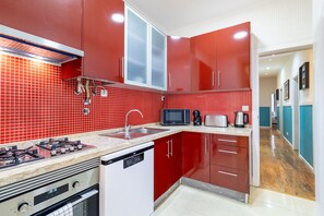 Une cuisine avec des meubles de rangement rouges, un four à micro-ondes, un grille-pain et un lave-vaisselle.