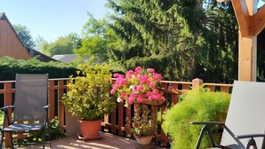 Une terrasse couverte avec deux chaises, des plantes en pot et une clôture en bois.