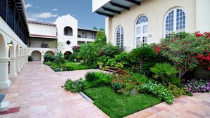 A courtyard with a paved walkway, surrounded by lush greenery and flowering plants. - Spacious Pet-Friendly Riverside Suite 3 Units w/ Grill & Bar, Pool & Hot Tub (Laredo)