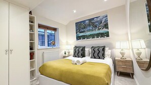 A bedroom with a bed, a window, a painting, and a nightstand. - Delightful 1-Bedroom w/ Garden in Queen’s Park near Notting Hill & Little Venice (London)