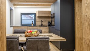 Eine kompakte Küche mit Holzbalken, einem schwarzen Kühlschrank und einem Essbereich mit Holztisch und Stühlen.