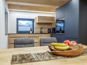 A modern kitchen with wooden cabinets, a built-in oven, and a window with a view of the outdoors. - Modern Holiday Home in the Heart of Grossarl (Grossarl)