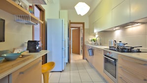 A modern kitchen with a refrigerator, stove, sink, and bar stools. - Casa Elena Cozy Stay Steps From Metro Station (Milan)