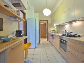 A modern kitchen with a refrigerator, stove, sink, and bar stools. - Casa Elena Cozy Stay Steps From Metro Station (Milan)