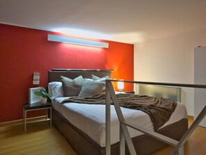 A modern hotel room with a bed, bedside table, and a red accent wall. - Loft Alessandra Brera Design Hideaway (Milan)