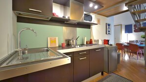 A modern kitchen with a stainless steel sink, a microwave, and a coffee maker. There is a dining area with a table and chairs. - Loft Alessandra Brera Design Hideaway (Milan)