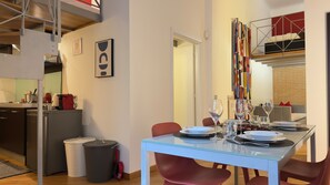 A modern dining area with a glass table set for four, red chairs, and a kitchen in the background. - Loft Alessandra Brera Design Hideaway (Milan)