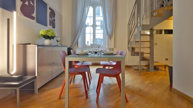 A modern kitchen with a dining area, wooden flooring, and a staircase leading to an upper level. - Loft Alessandra Brera Design Hideaway (Milan)