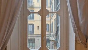 A window with a white frame and a view of a narrow street with buildings. - Loft Alessandra Brera Design Hideaway (Milan)