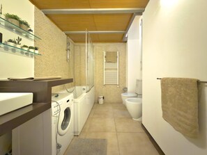 A compact bathroom with a washing machine, a toilet, and a glass shelf with plants. - Loft Alessandra Brera Design Hideaway (Milan)