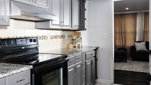 Une cuisine moderne avec un four noir, des armoires grises et un pare-feu en carreaux.
