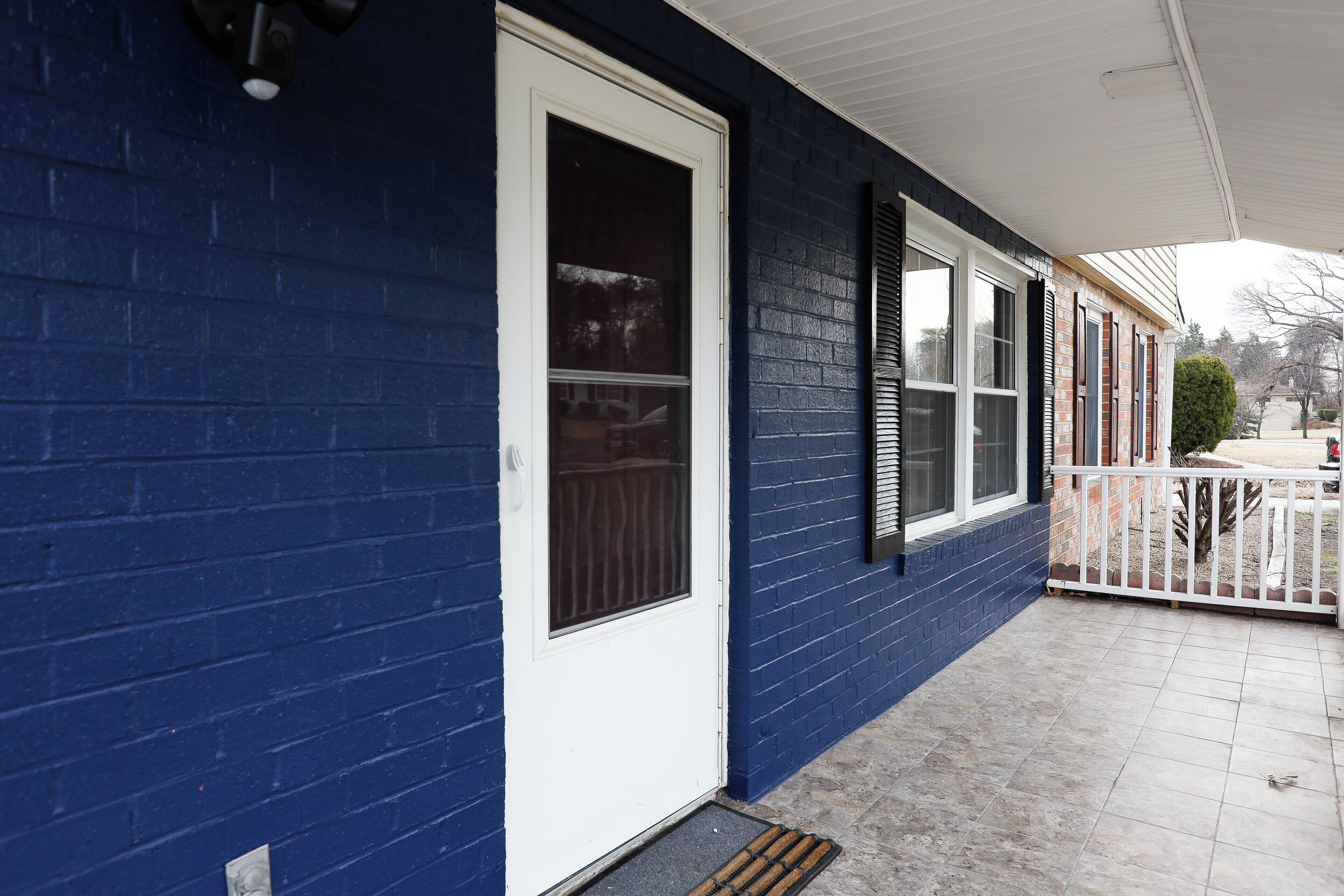 Ein Haus mit blauer Fassade, einer weißen Tür und einer Veranda mit weißem Geländer.