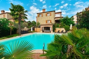 A pool area with a stone building, palm trees, and lounge chairs. - Villa mit Pool in Kastelir fur 9 Personen (Kastelir-Labinci)