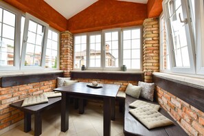 A cozy corner with a dark wooden table and benches, brick walls, and large windows offering a view of buildings outside. - Villa mit Pool in Kastelir fur 9 Personen (Kastelir-Labinci)
