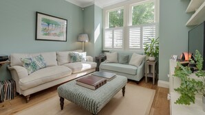 A living room with two sofas, a coffee table, a lamp, and a TV. - Wild Roses in London (London)