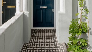 A white building with a dark blue door, white columns, and a checkered floor. - Wild Roses in London (London)