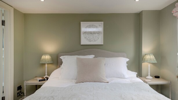 A neatly made bed with white linens, two bedside tables with lamps, and a framed artwork on the wall. - Wild Roses in London (London)