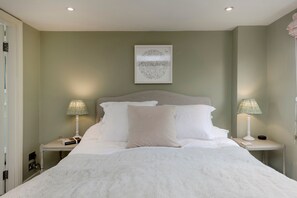 A neatly made bed with white linens, two bedside tables with lamps, and a framed artwork on the wall. - Wild Roses in London (London)