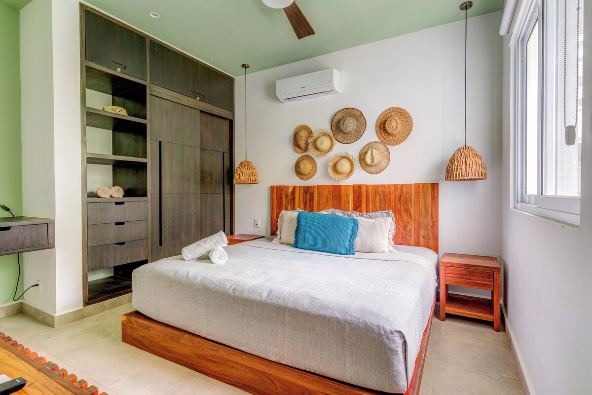 A neatly arranged bedroom with a bed, a wardrobe, a bedside table, and a wall-mounted air conditioner.