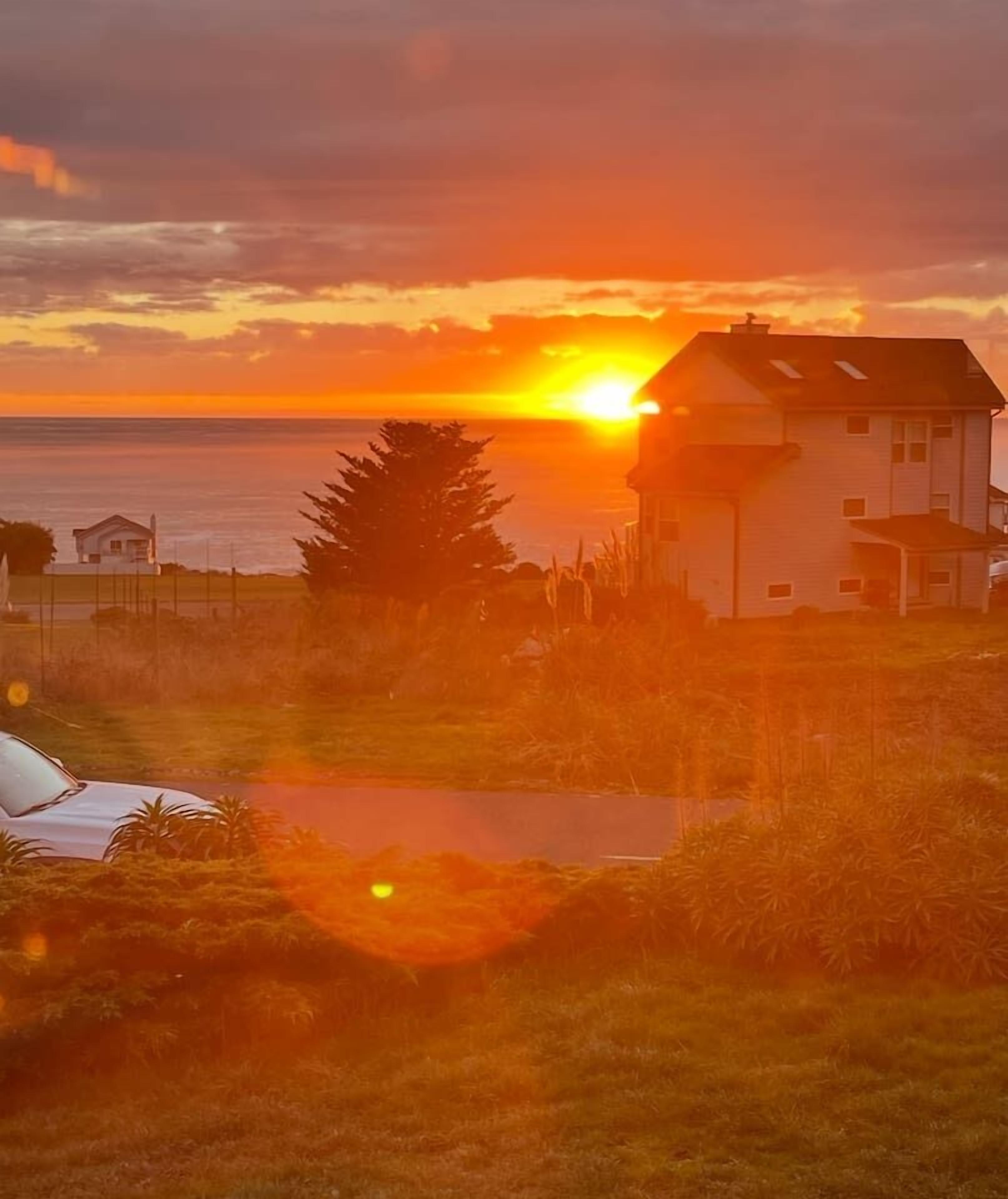 A house with a view of the sunset over the ocean.