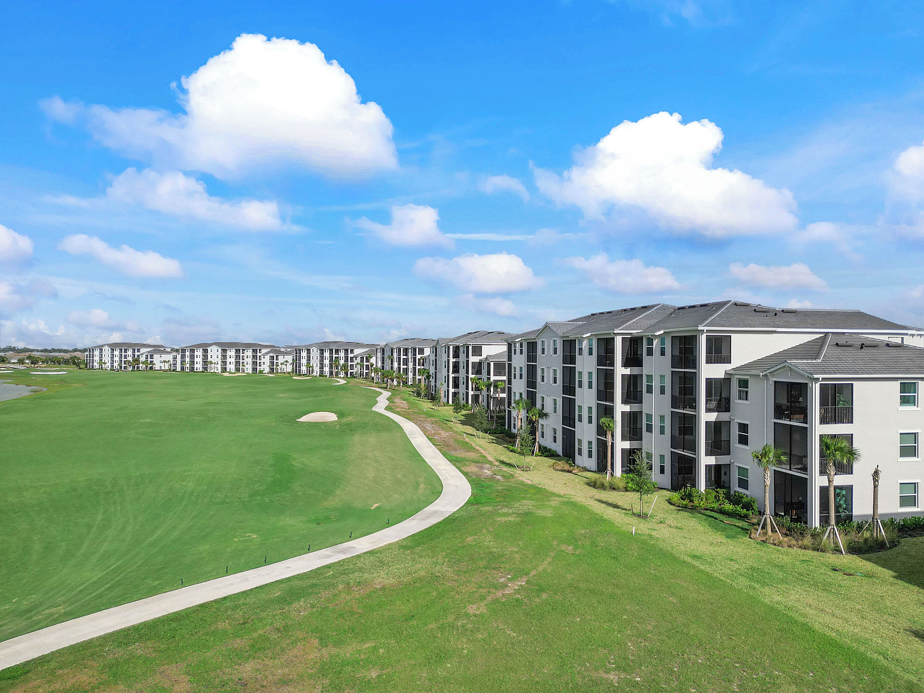 Een modern appartementencomplex met een golfbaan op de voorgrond.