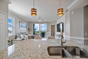 A kitchen with a granite countertop, stainless steel sink, and pendant lighting. - Golf Luxe 3-Bedroom Condo at Babcock Ranch, Florida (Punta Gorda)