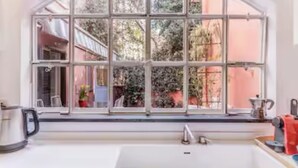 A kitchen with a large window, a sink, and a kettle. - Deco Garden Apartment Trastevere (Roma)