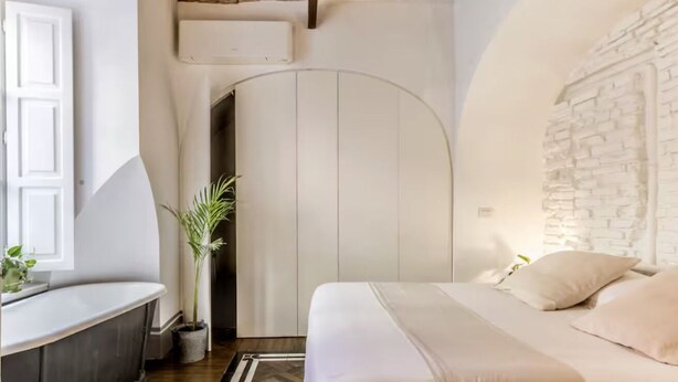 A bedroom with a bed, a nightstand, a potted plant, and a white wardrobe. - Deco Garden Apartment Trastevere (Roma)