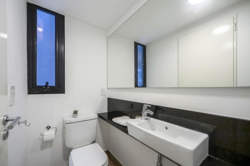 A compact bathroom with a toilet, sink, and a mirror above the sink.