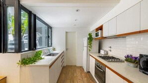 A compact kitchen with white cabinets, a stainless steel sink, a microwave, and a gas stove. - MOT Honduras 5766 (Buenos Aires)