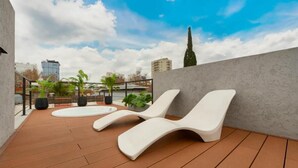 A rooftop terrace with two white lounge chairs, a wooden deck, and potted plants. - MOT Honduras 5766 (Buenos Aires)