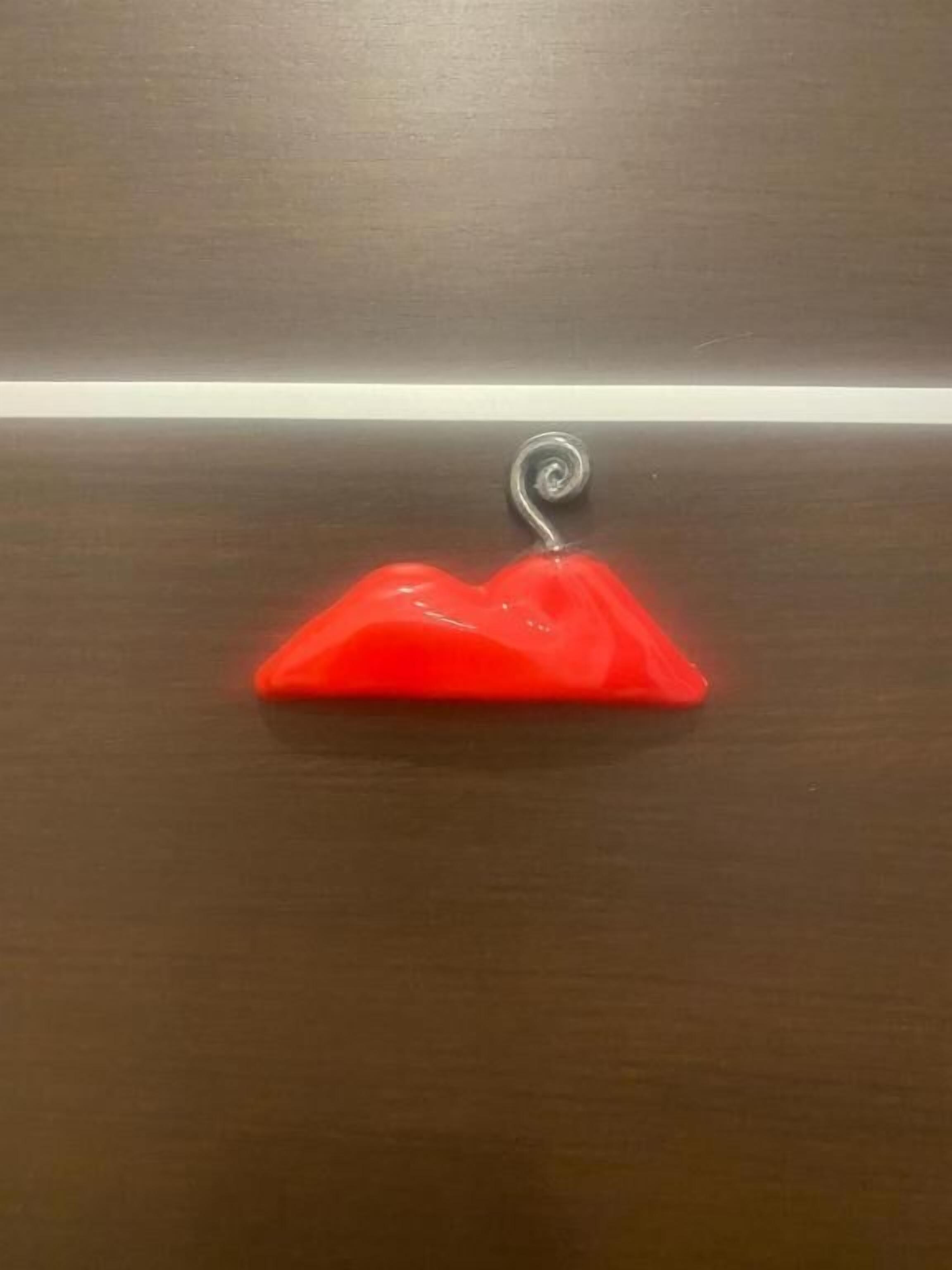 Un cintre en plastique rouge posé sur une surface en bois.